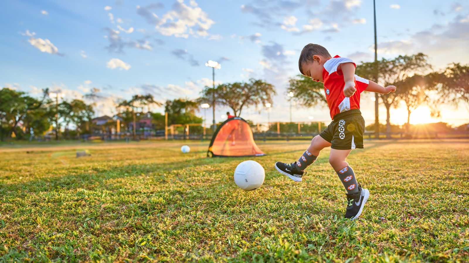 Boy in a Soccer Shots jersey kicks a ball.
