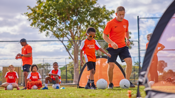 Soccer Shots coach and boy dribbling to goal