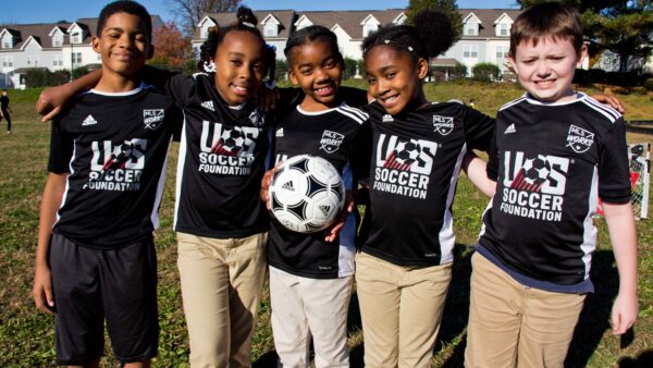 Group of children all wearing US Soccer Foundation jerseys in a huddle