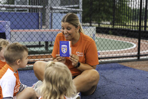 Coach showing Global Goals passports to children