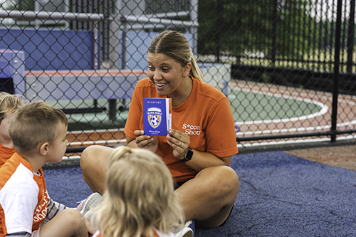 Coach showing Global Goals passports to children