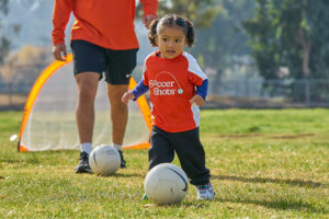 Coach and Child Kicking Soccer Ball